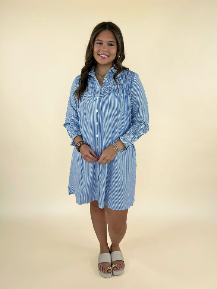 Front full body view of women’s blue and white striped button down shirt dress styled with slide sandals
