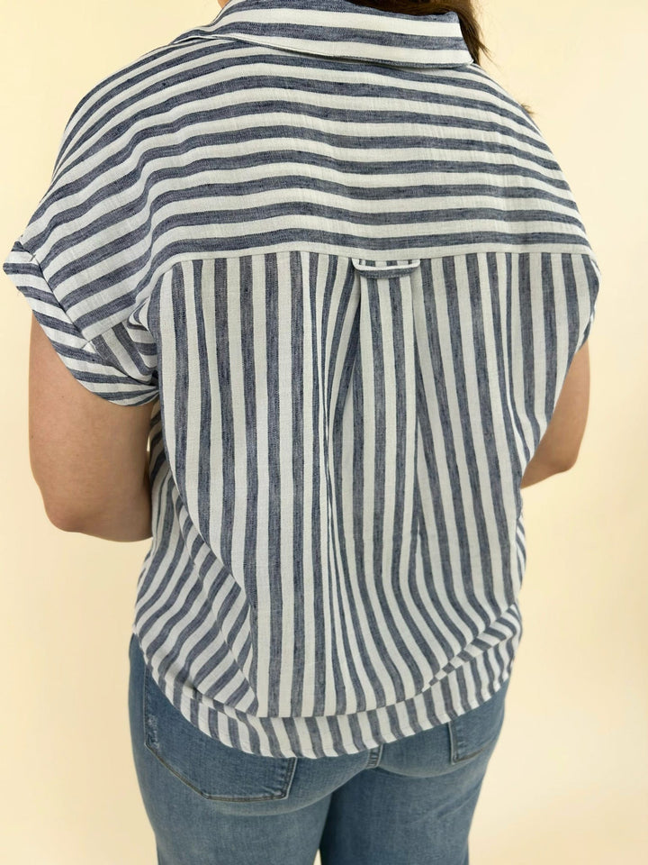Back view of blue and white striped short sleeve blouse with mixed stripe pattern and relaxed fit paired with denim jeans