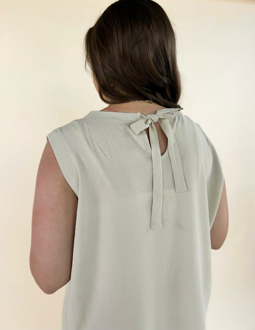 Back detail of cream sleeveless top featuring tie closure neckline and lightweight fabric