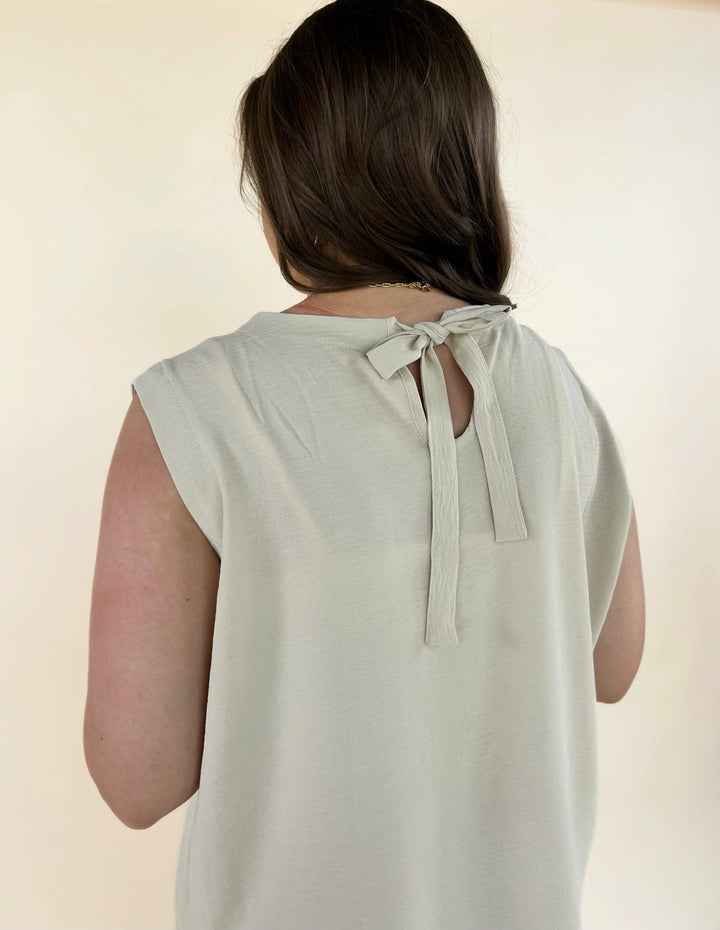 Back detail of cream sleeveless top featuring tie closure neckline and lightweight fabric