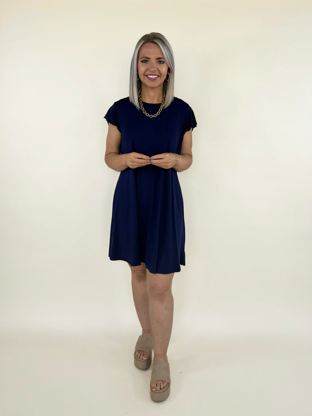 Front view of navy short sleeve swing dress with relaxed fit and above the knee length styled with platform sandals