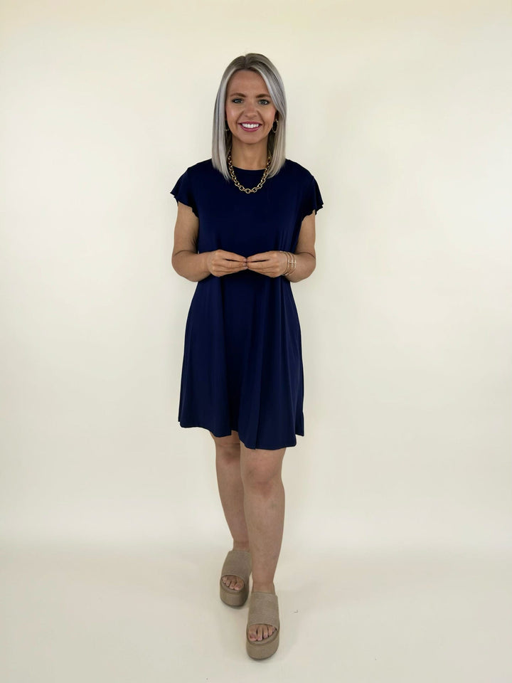 Front view of navy short sleeve swing dress with relaxed fit and above the knee length styled with platform sandals