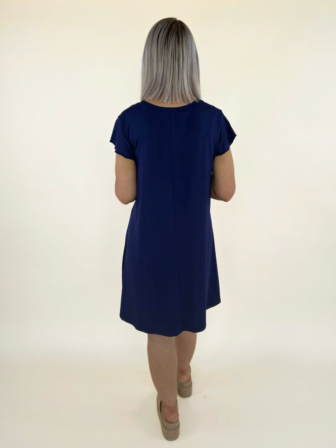 Back view of navy short sleeve swing dress with relaxed fit and flowy silhouette styled with platform sandals