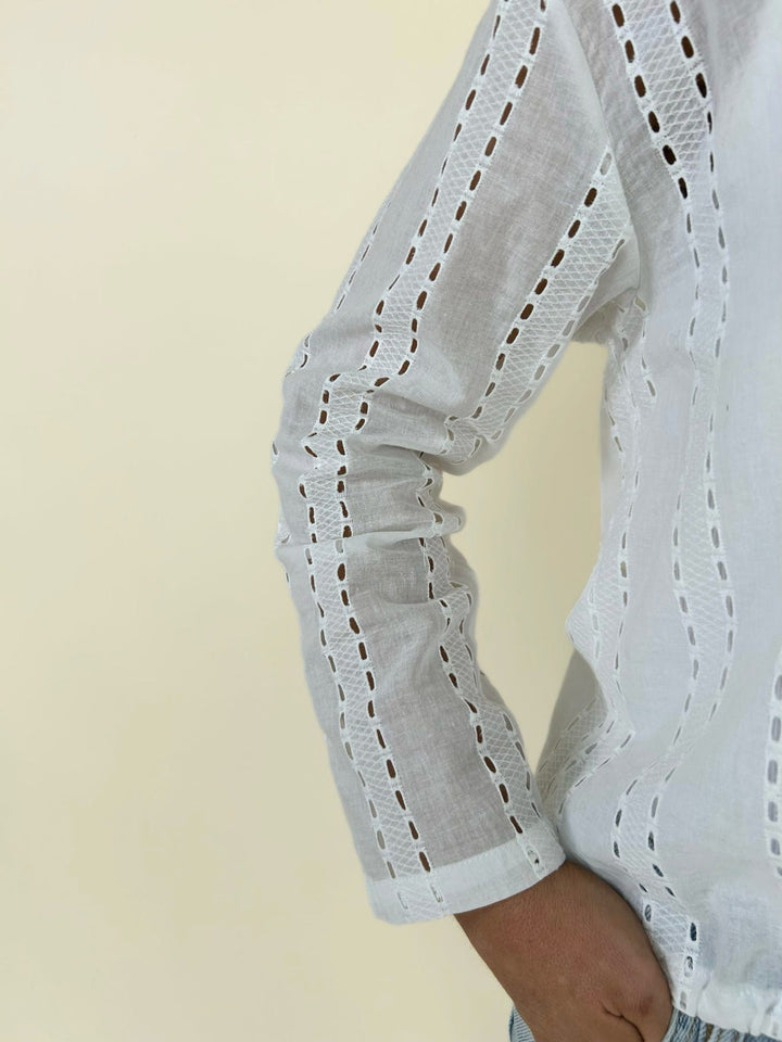 Close up sleeve detail of white eyelet blouse showing breathable fabric, long sleeve fit, and delicate cutout design