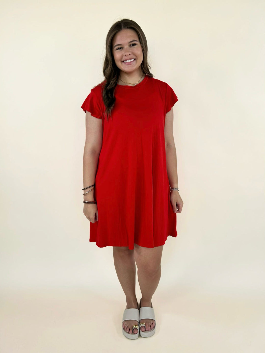 Front full body view of red short sleeve swing dress styled with slide sandals