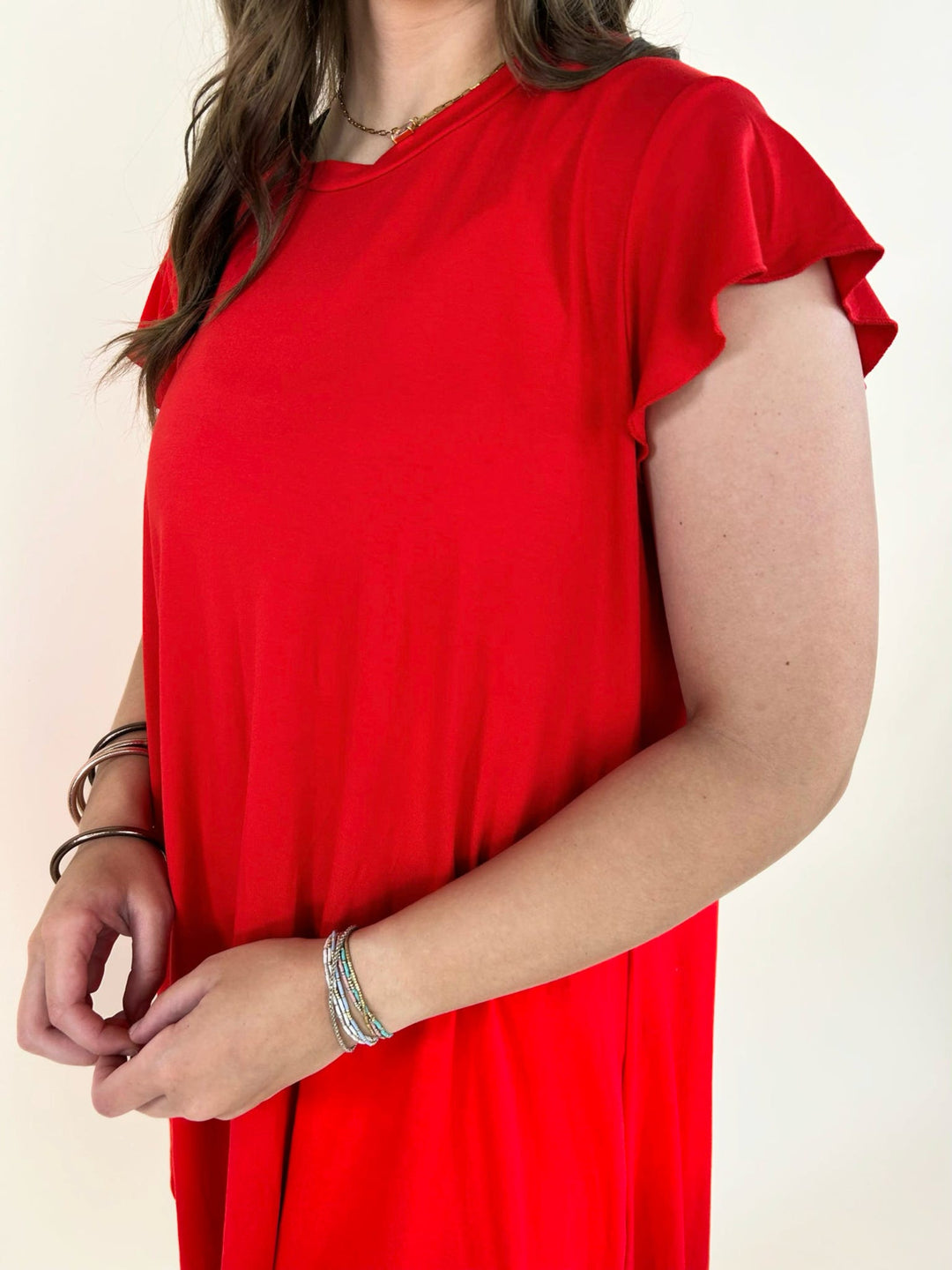 Close up detail of red short sleeve dress showing soft fabric and flutter sleeve design