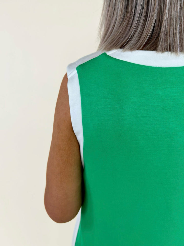 Close-up back detail of green dress showing white trim neckline and smooth fabric finish