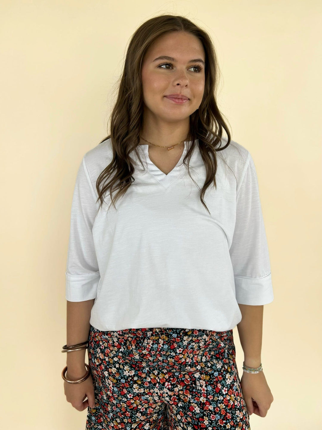 Women’s white V-neck top styled with black floral pants, casual chic boutique outfit front view