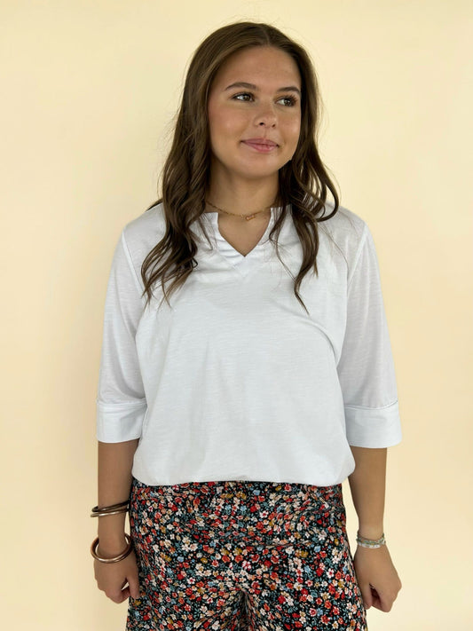 Women’s white V-neck top styled with black floral pants, casual chic boutique outfit front view