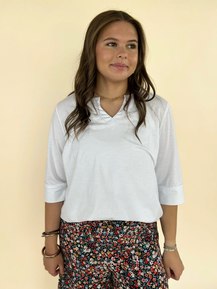 Women’s white V-neck top styled with black floral pants, casual chic boutique outfit front view