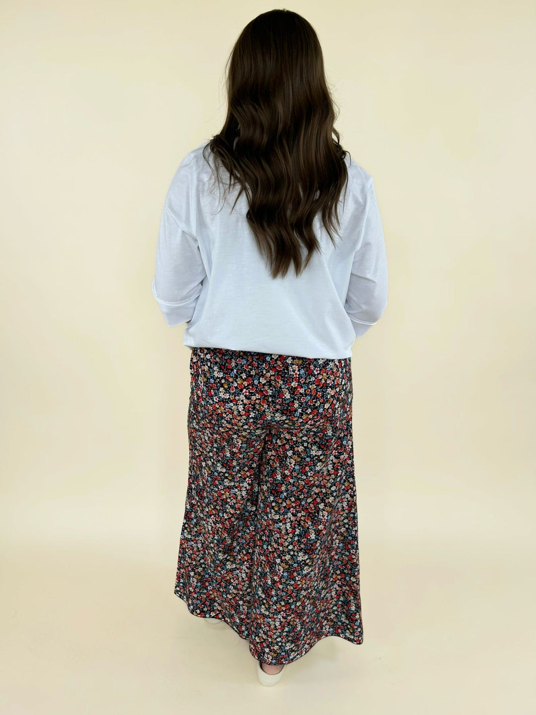 Back view of white blouse with 3/4 sleeves paired with black floral wide-leg pants, women’s casual outfit