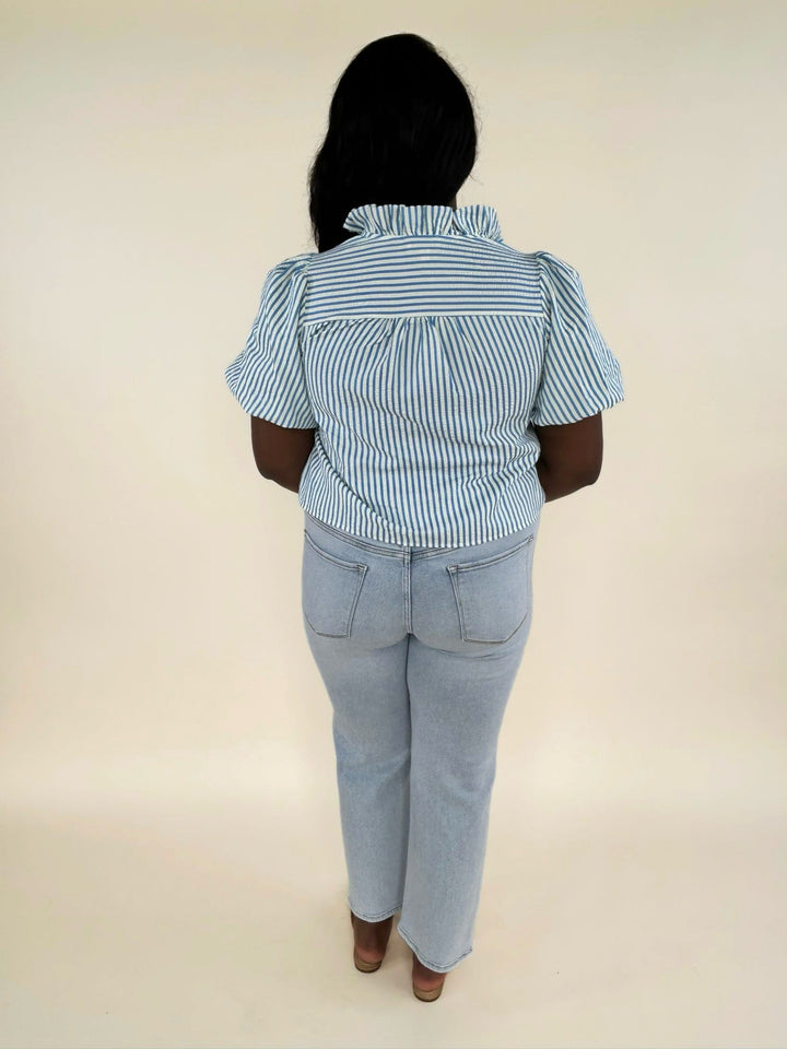 Back view of blue and white striped blouse with ruffle collar and light wash straight leg jeans, women’s boutique fashion