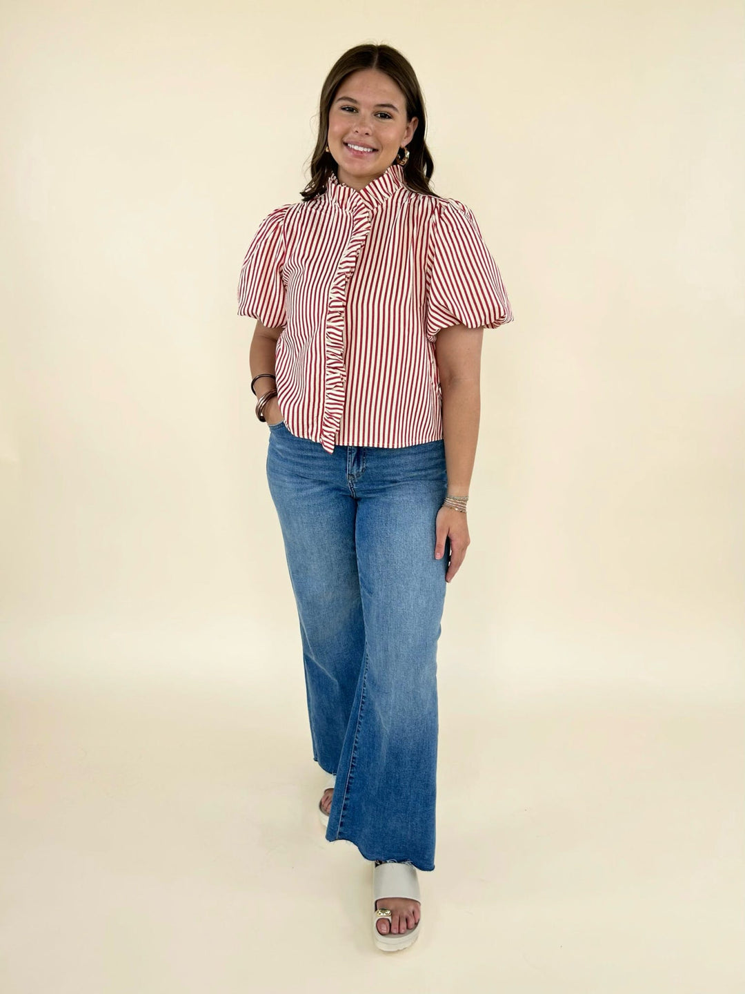 red and white striped ruffle blouse with puff sleeves paired with wide leg blue jeans and slide sandals