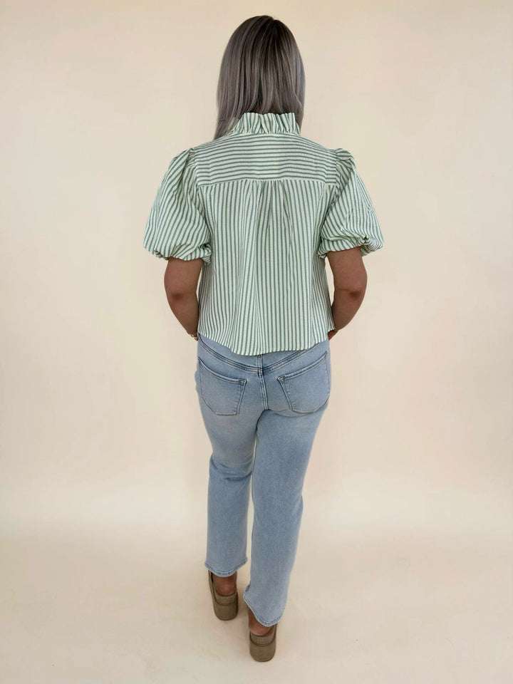 Back view of green striped ruffle blouse with puff sleeves paired with light wash denim jeans, casual spring women’s fashion