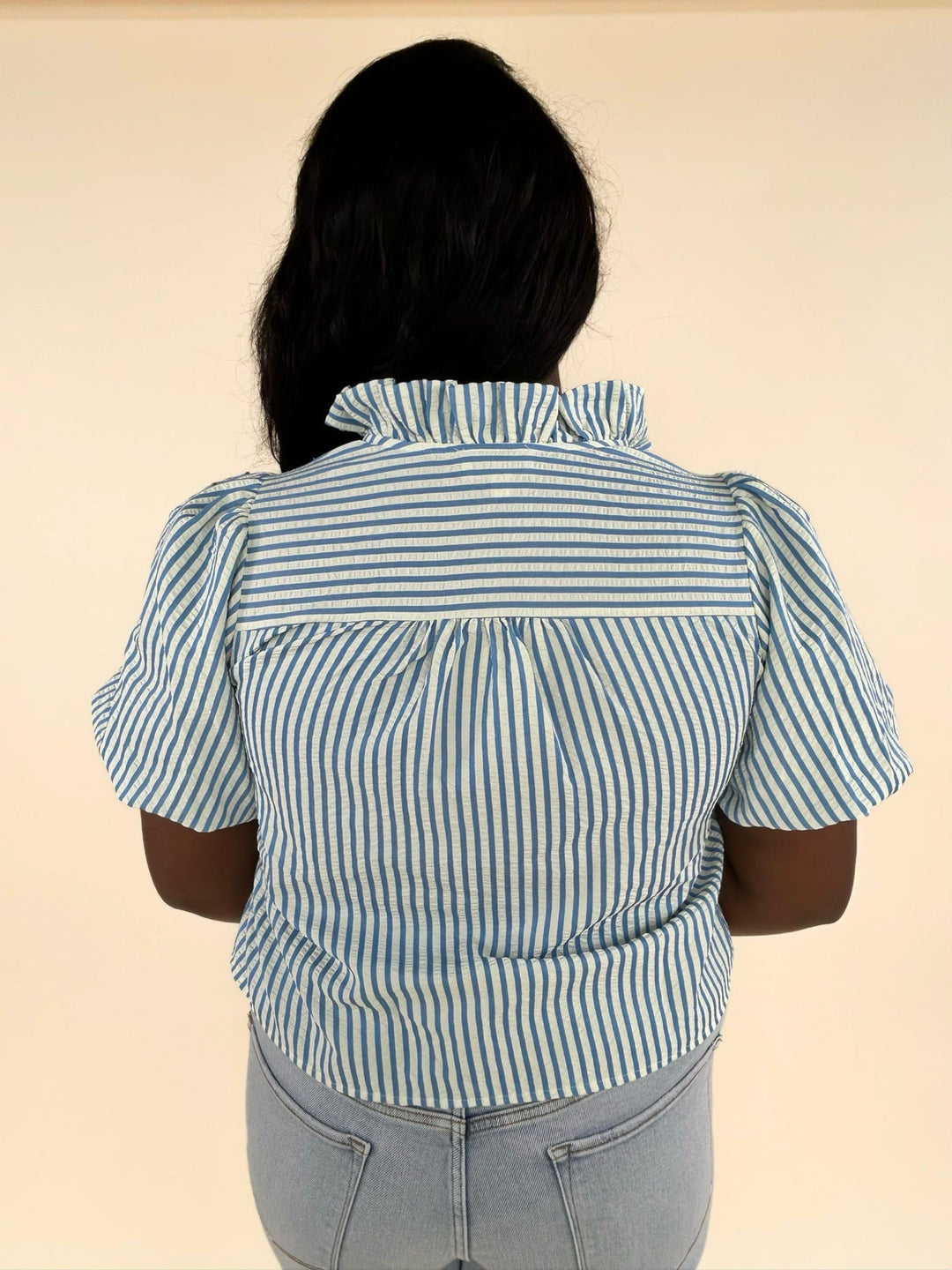 Close-up back detail of blue striped ruffle blouse showing gathered yoke and vertical stripe pattern
