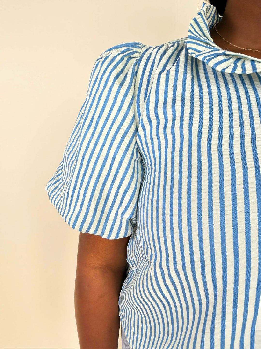 Close-up sleeve detail of blue striped blouse highlighting puff sleeve and textured stripe fabric