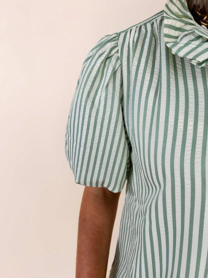 Close-up sleeve detail of green striped blouse showing puff sleeve structure and textured stripe fabric