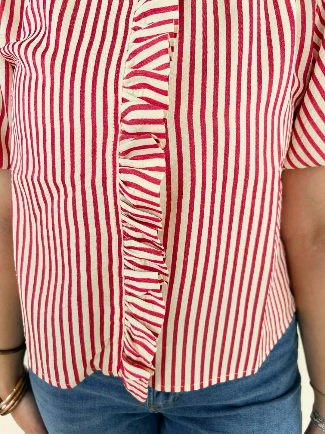 Close up of red and white striped ruffle front blouse detailing vertical stripes and button front design