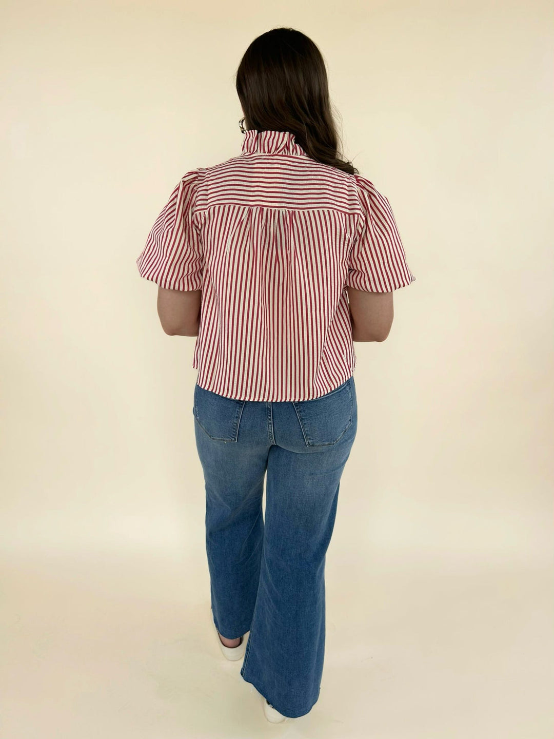 Back view of red and white striped blouse with gathered detail and wide leg blue jeans outfit