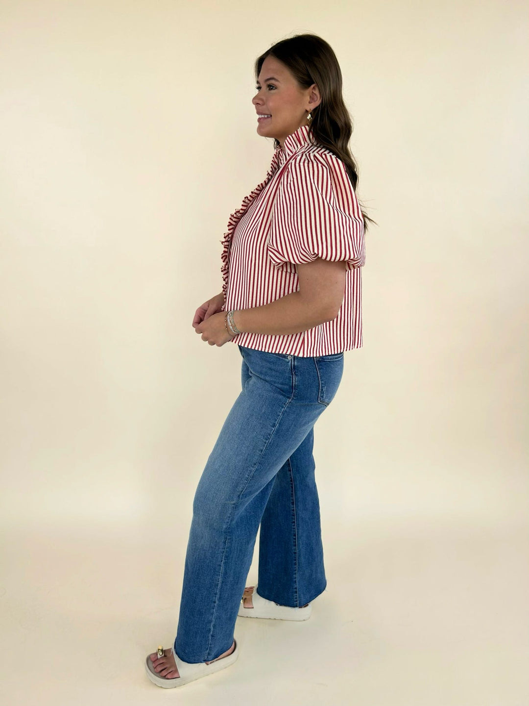 Side view of red and white striped puff sleeve blouse styled with high waisted wide leg denim jeans and neutral slide sandals