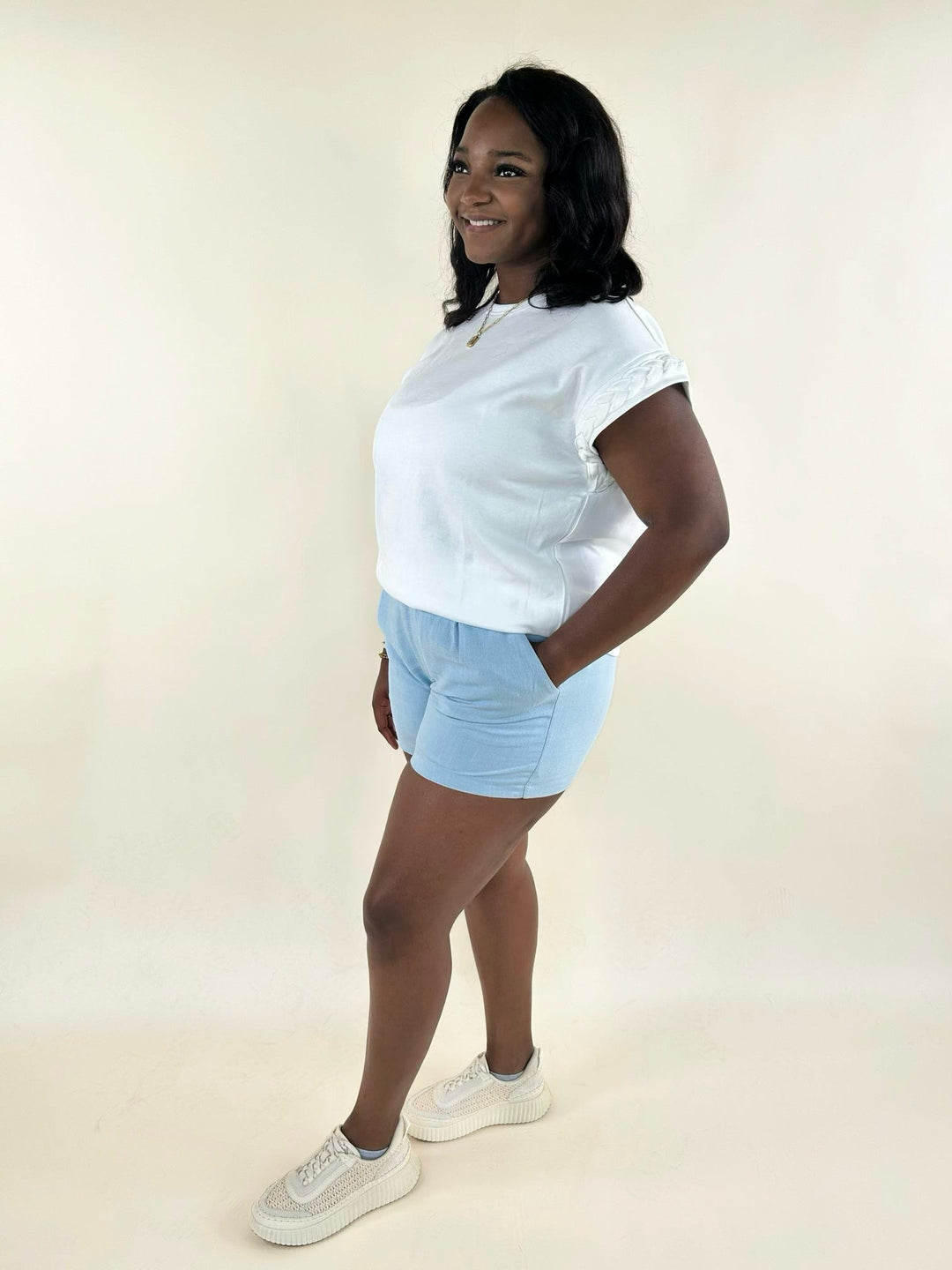White short sleeve top with braided sleeve detail, crew neckline, relaxed silhouette, and casual styling with light blue shorts