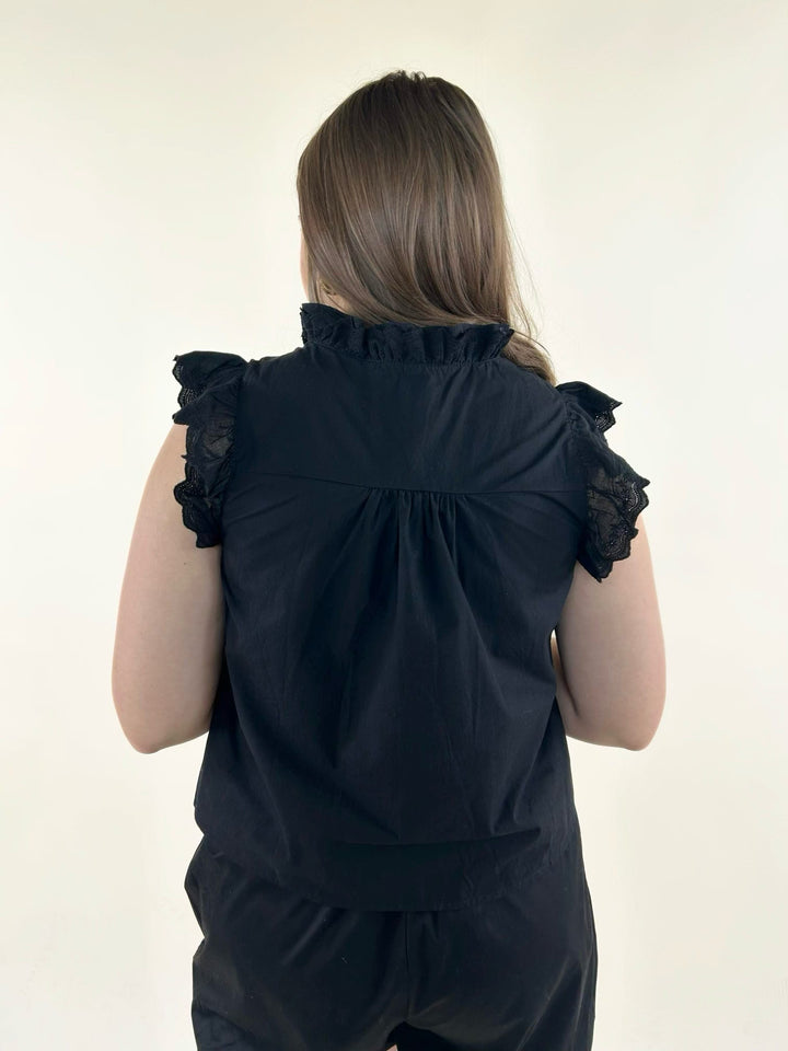 Back view of black ruffle neck blouse with gathered yoke detail, lace flutter sleeves, and elegant tailored styling