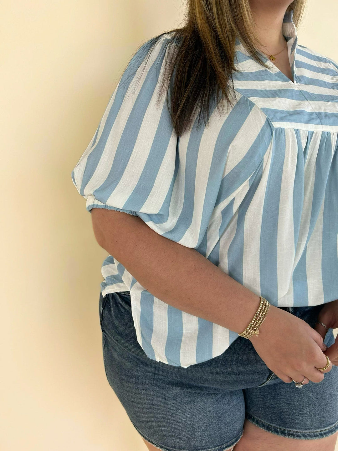 Detailed front view of striped collared blouse with pleated front panel and relaxed fit