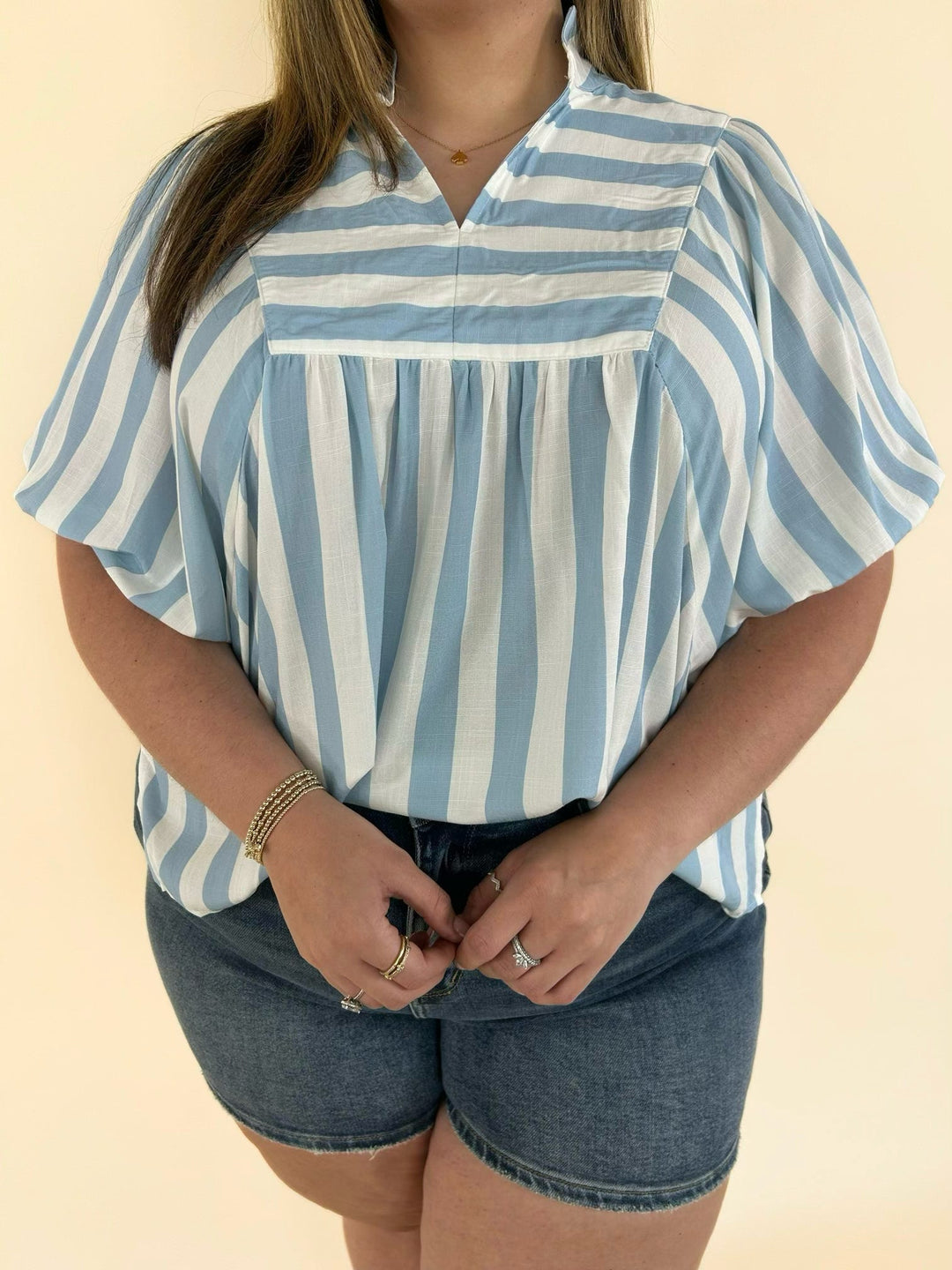 Close-up of blue and white striped blouse with collared neckline and flutter puff sleeve