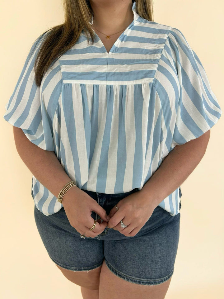 Close-up of blue and white striped blouse with collared neckline and flutter puff sleeve