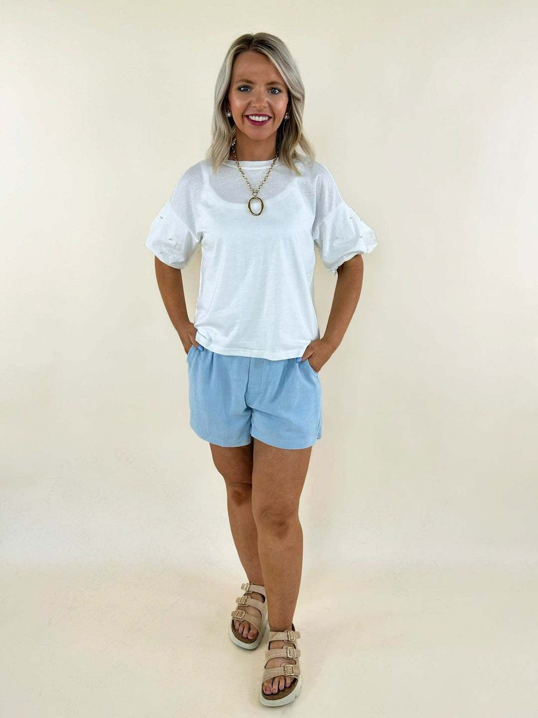 White pearl puff sleeve top paired with light blue shorts and neutral sandals for a polished casual summer look