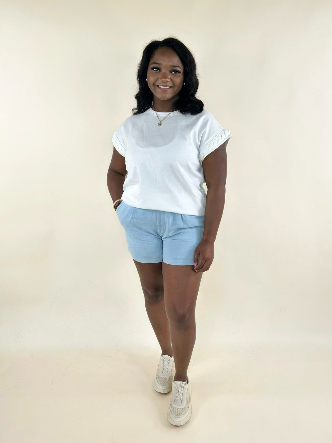 White braided sleeve top styled with light blue shorts and sneakers, creating a casual and comfortable summer outfit