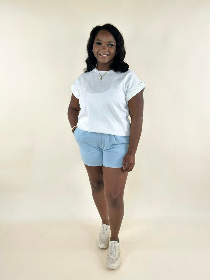 White braided sleeve top styled with light blue shorts and sneakers, creating a casual and comfortable summer outfit