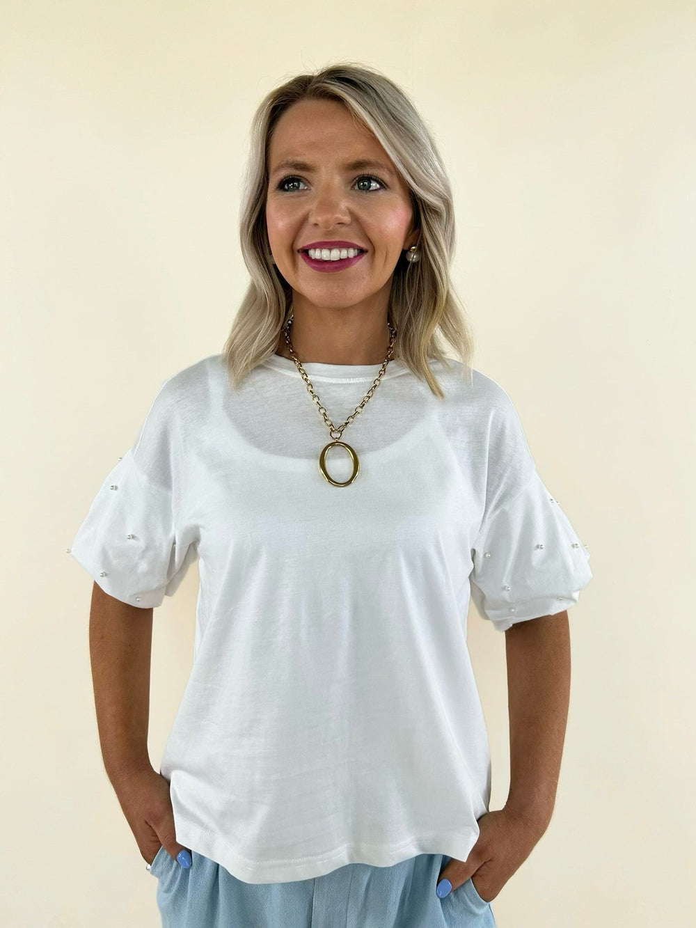 Women's white pearl embellished puff sleeve top with crew neckline, relaxed fit, and elegant casual styling paired with light blue shorts