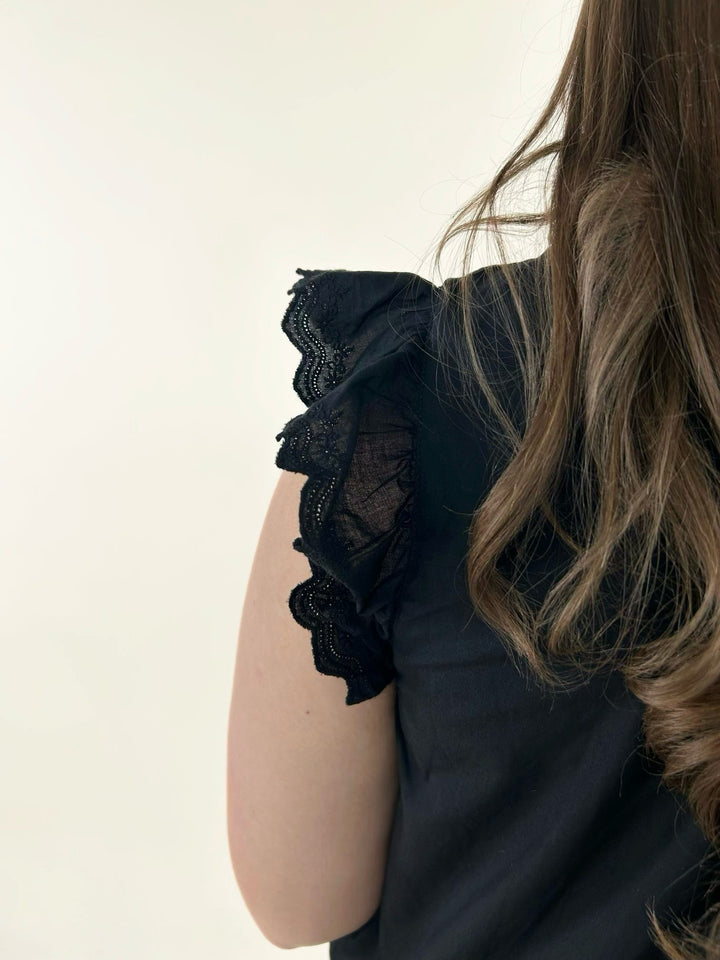 Close-up of black lace ruffle sleeve detail featuring scalloped trim and feminine layered flutter sleeve design
