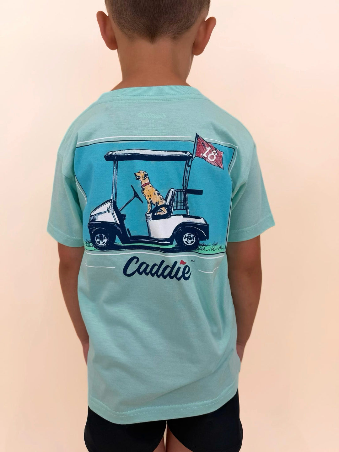 Youth Caddie graphic t-shirt featuring golf cart, Labrador retriever, and golf flag design, boys golf-themed shirt, outdoor lifestyle apparel for kids