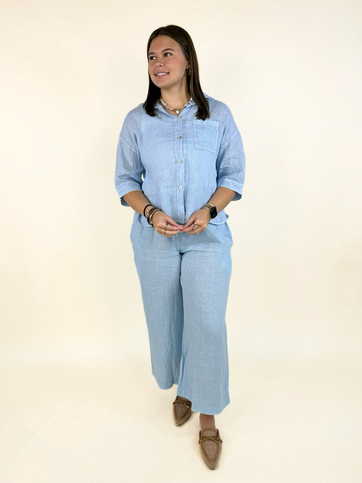 Matching light blue linen button-down shirt and wide-leg pants set featuring breathable natural fabric, an elastic drawstring waistband, side pockets, and a relaxed silhouette for effortless everyday style.