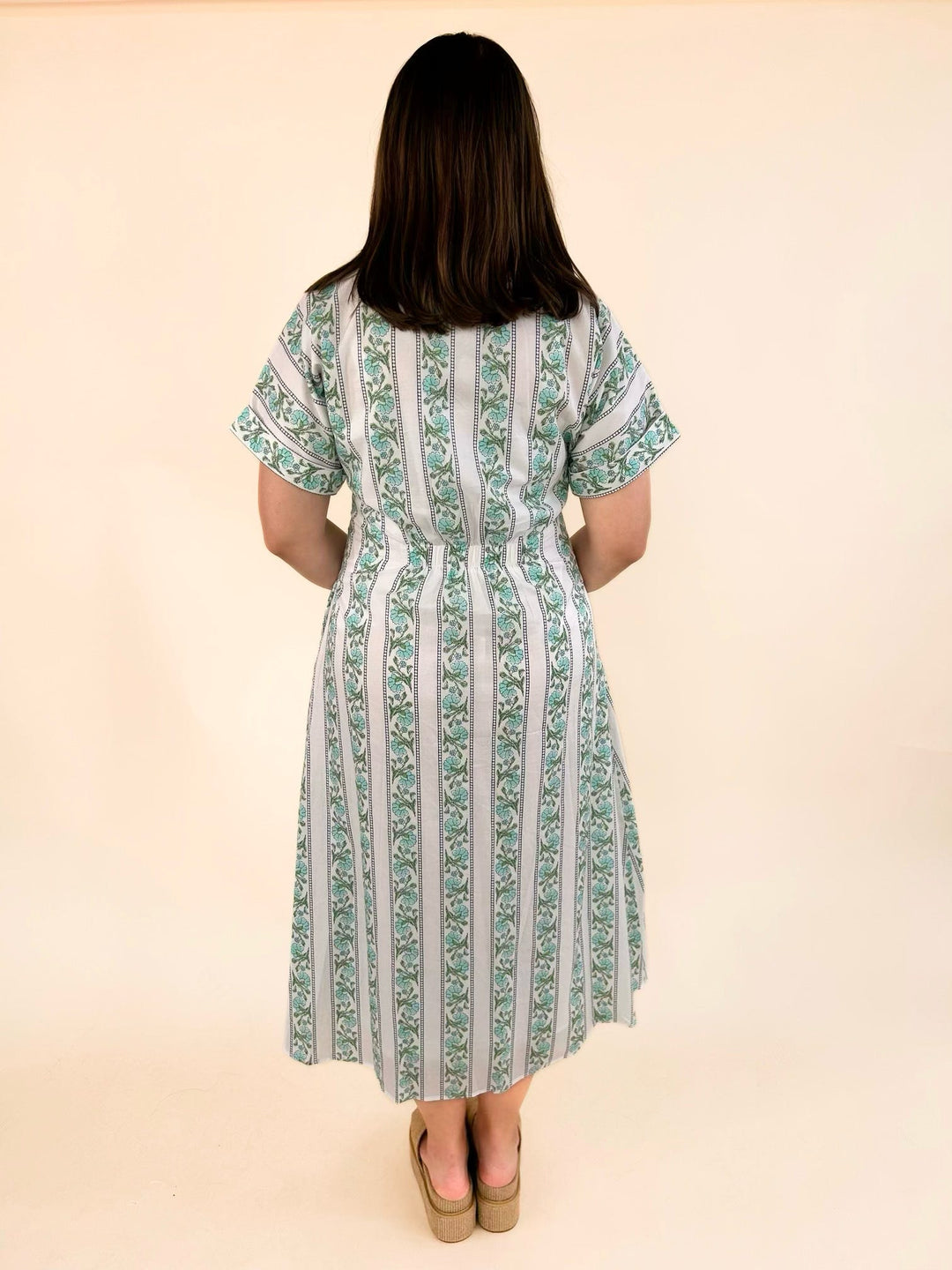 Back view of the white floral stripe button-front midi dress with a collared neckline, short sleeves, fitted waist, and flowy midi-length skirt.