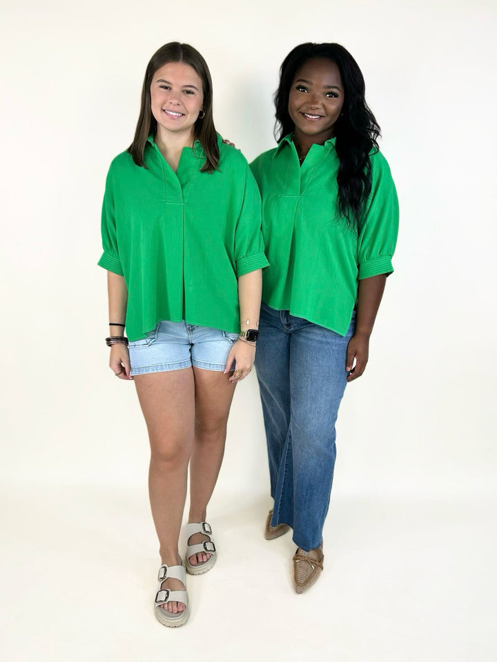 vibrant green collared short sleeve blouse with a relaxed fit, split neckline, cuffed sleeves, and lightweight woven fabric styled with denim shorts and jeans.