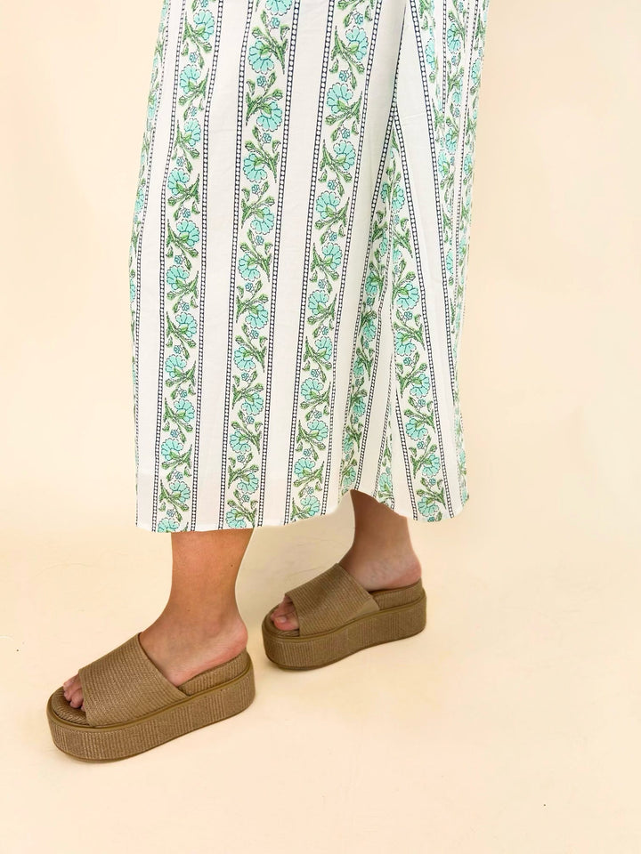 Close-up of the lower portion of the white floral stripe midi dress highlighting the side slit and flowy skirt paired with tan platform slide sandals.