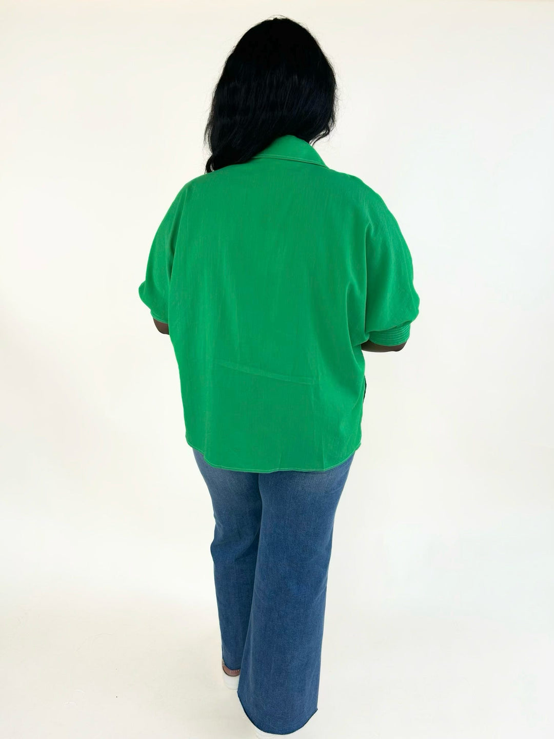 Back view of the vibrant green relaxed fit blouse featuring a collared neckline, cuffed short sleeves, and lightweight woven fabric.