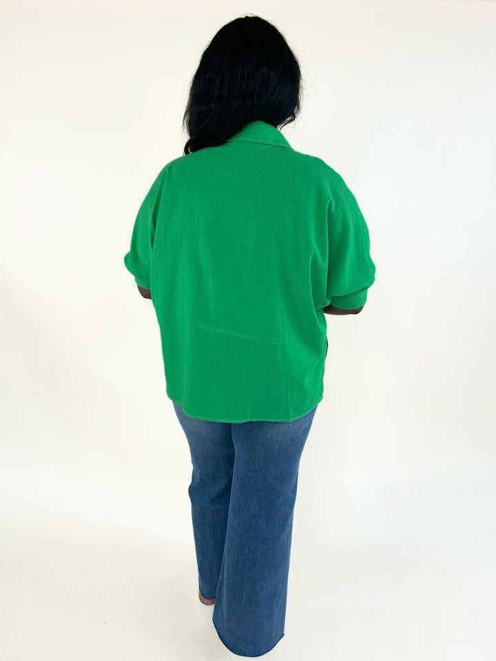 Back view of the vibrant green relaxed fit blouse featuring a collared neckline, cuffed short sleeves, and lightweight woven fabric.