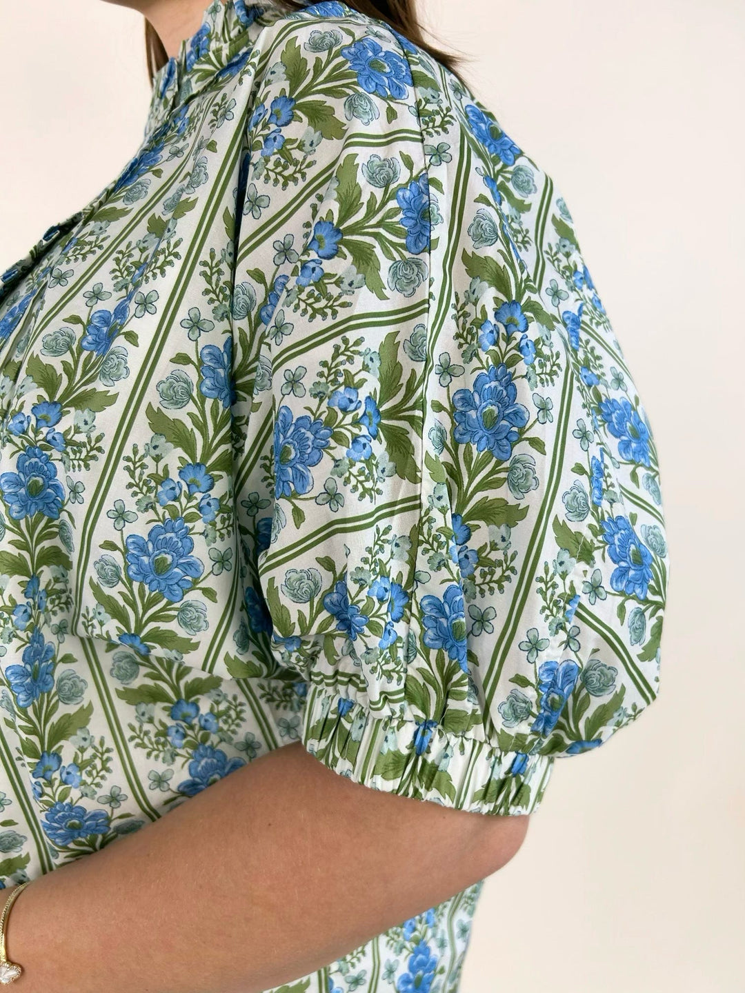 Close-up of blue botanical floral print with ruffle trim placket and puff sleeve detail