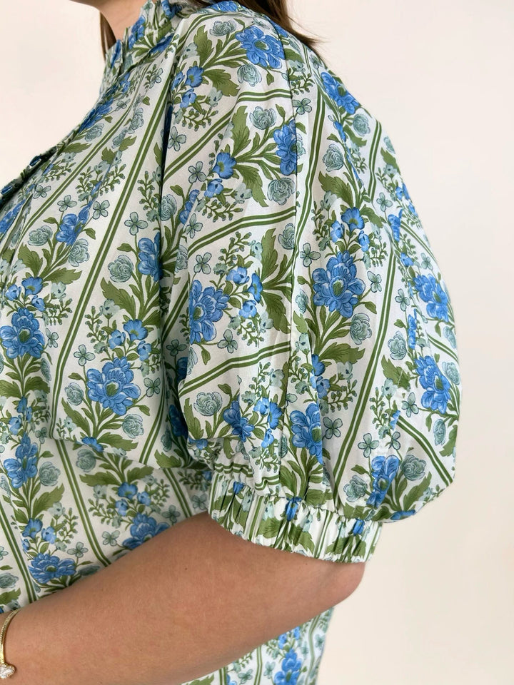 Close-up of blue botanical floral print with ruffle trim placket and puff sleeve detail