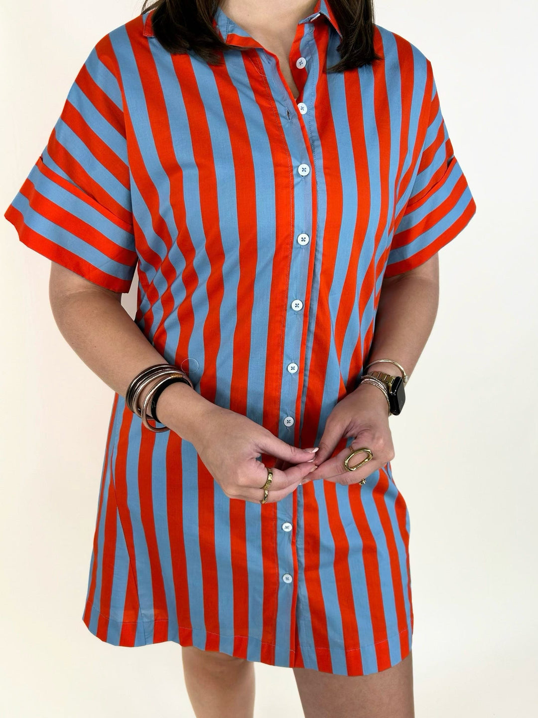 Close-up of the THML Weekend Getaway Striped Shirt Dress in blue with orange vertical stripes, showcasing the collared neckline, button-front closure, bold stripe pattern, and soft cotton fabric.