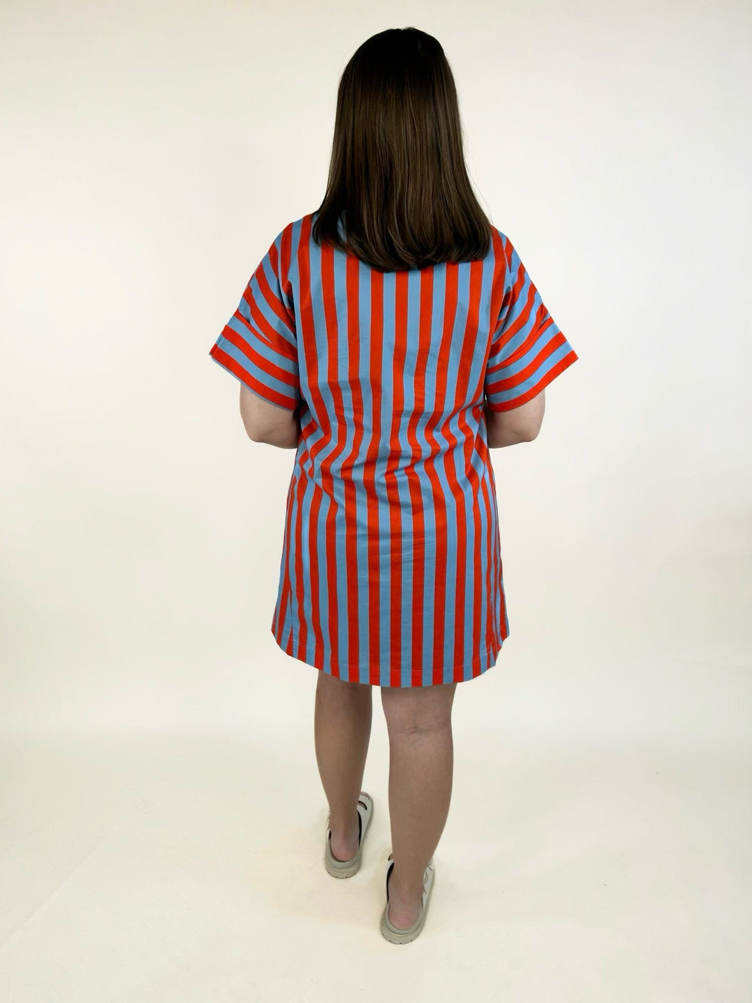Back view of the THML Weekend Getaway Striped Shirt Dress in blue with orange vertical stripes, showcasing the relaxed shirt dress silhouette, rolled short sleeves, and breathable cotton fabric.