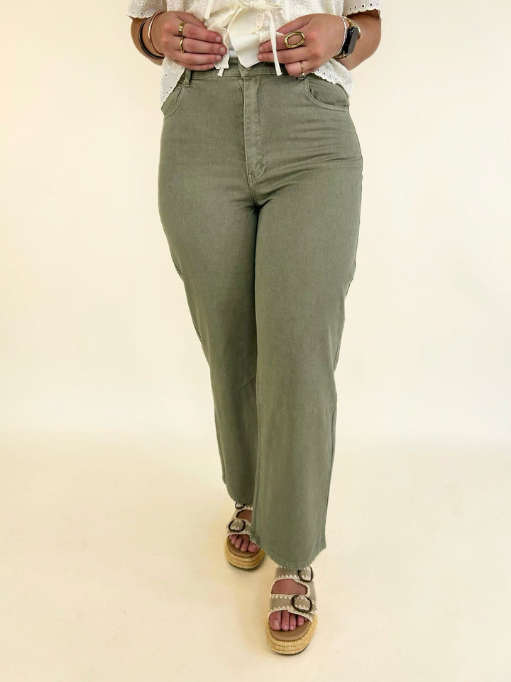 Front view of light olive wide leg jeans featuring a mid-rise waist, five-pocket styling, and washed cotton denim.