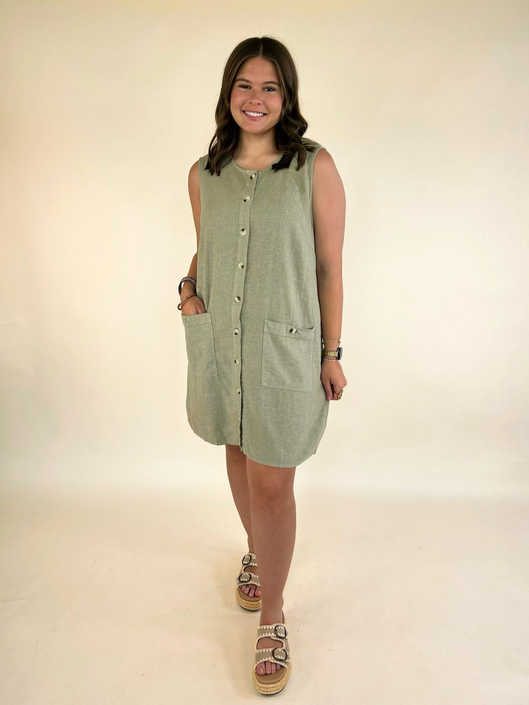 Dear John Riri linen blend sleeveless mini dress in Abbey Stone featuring a button-front design, front pockets, and relaxed fit.
