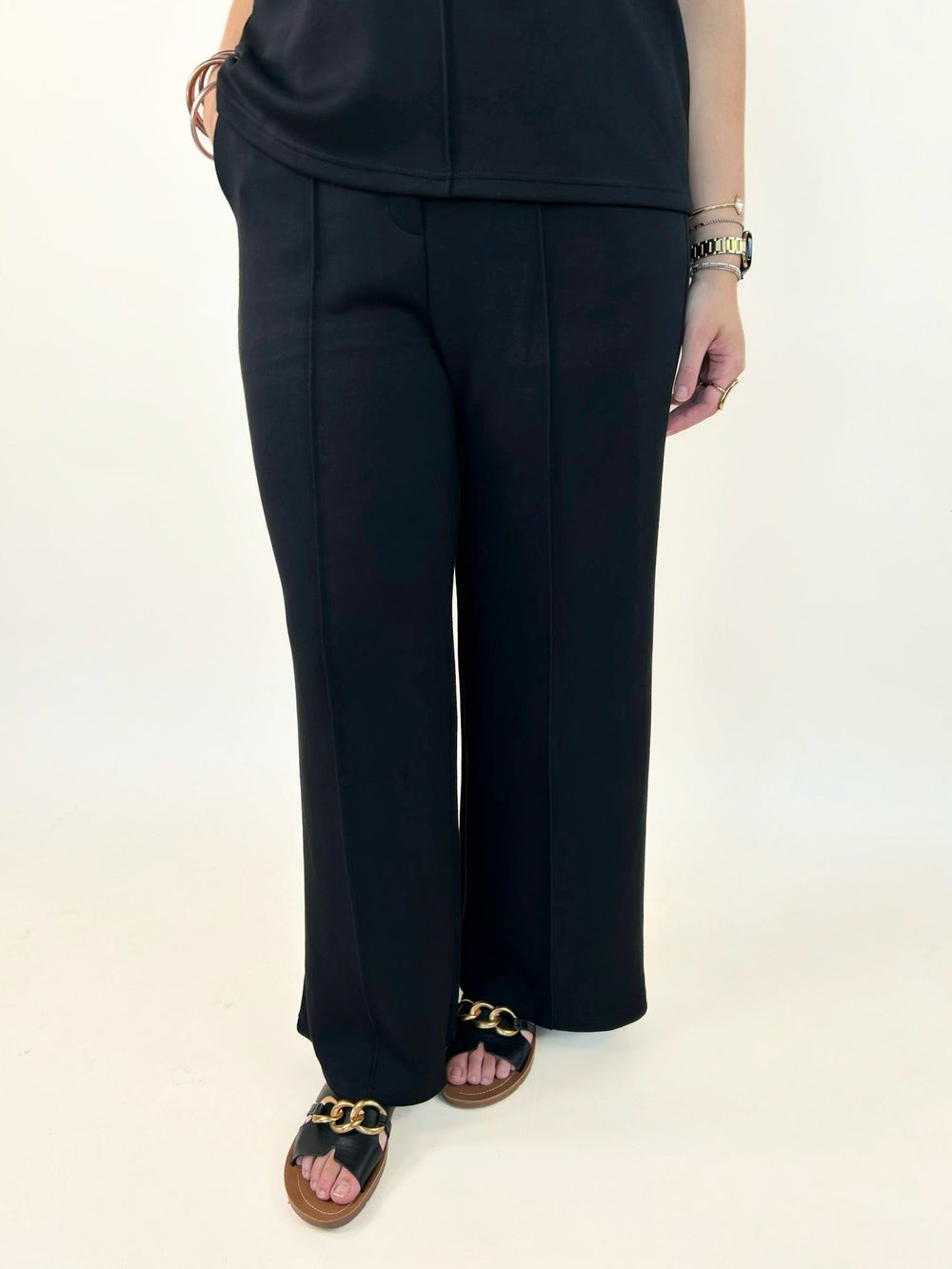Close-up of women's black wide leg pants featuring a flattering front seam detail, pull-on waistband, and soft stretch fabric.