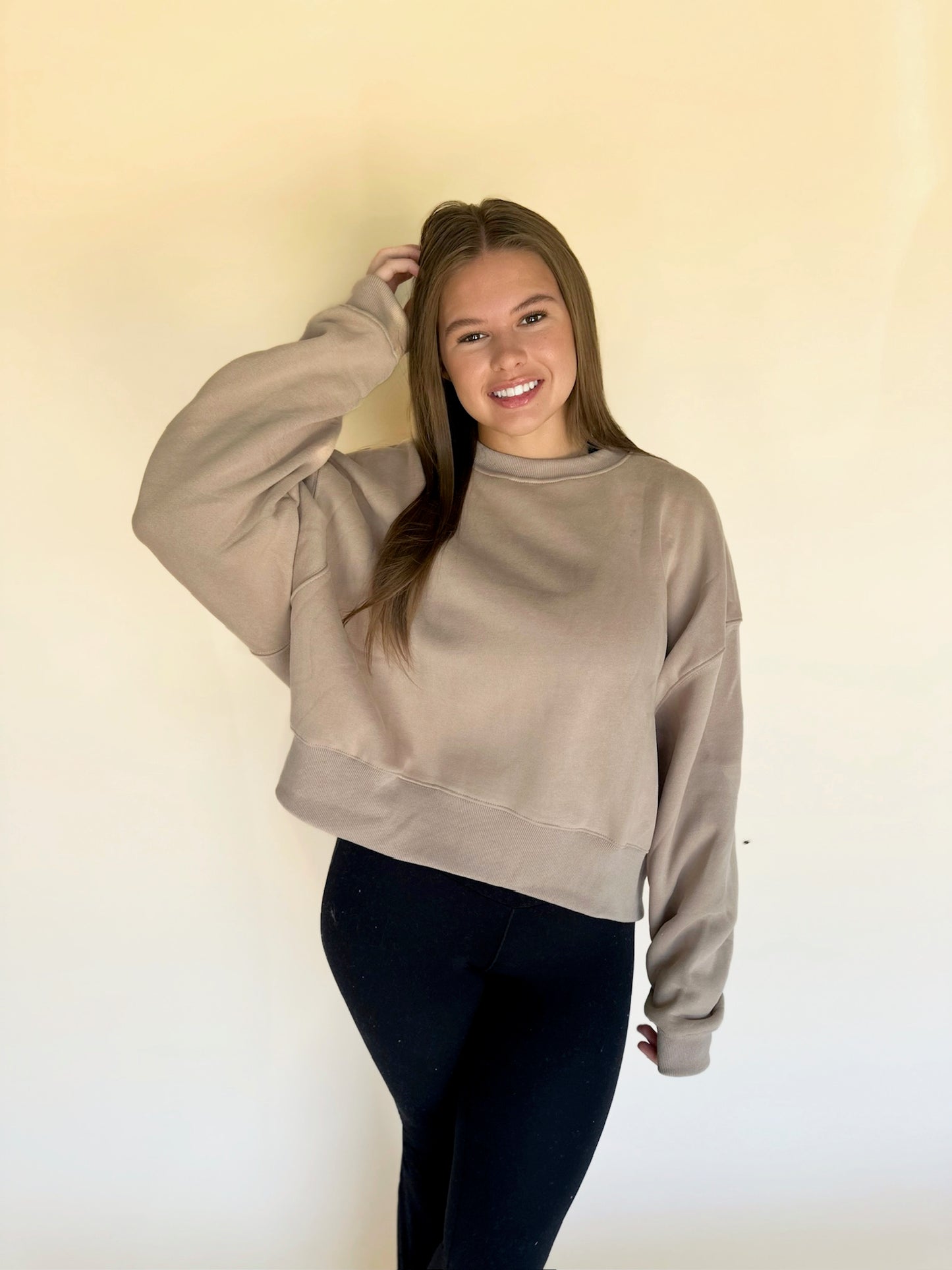Woman wearing a beige sweatshirt against a plain background