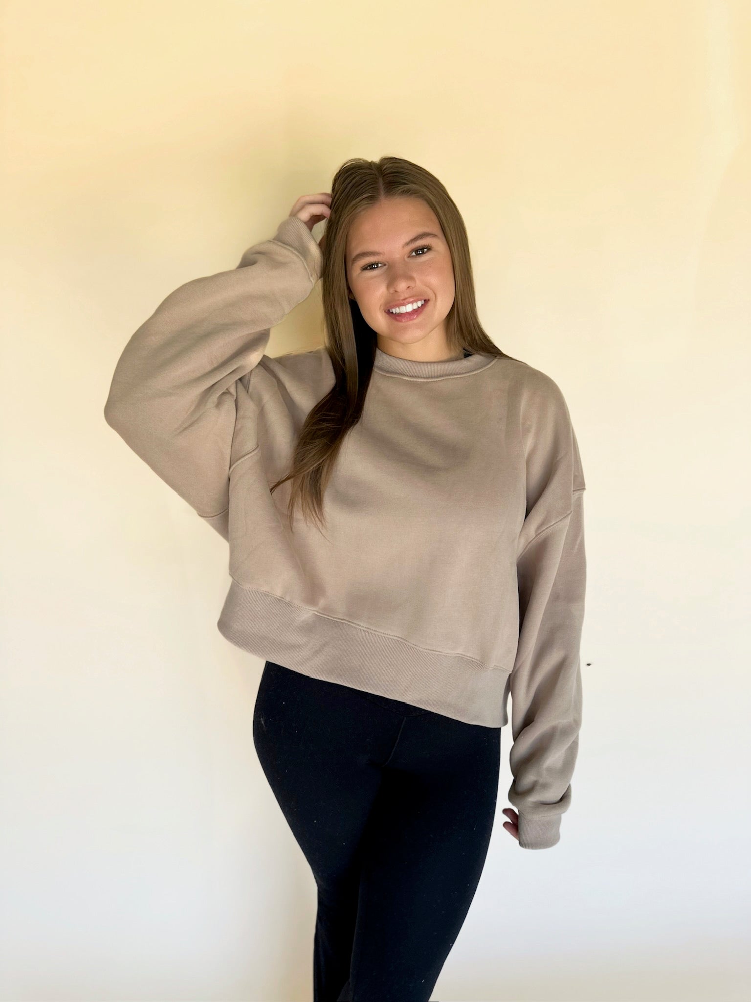 Woman wearing a beige sweatshirt against a plain background